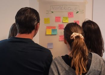 4 personnes collaborent devant un mur de post-its 